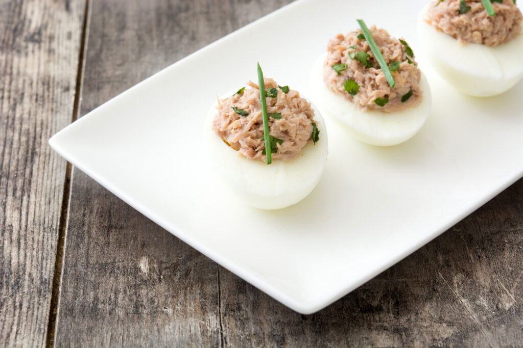 Hard boiled egg with tuna salad and chives on a plate